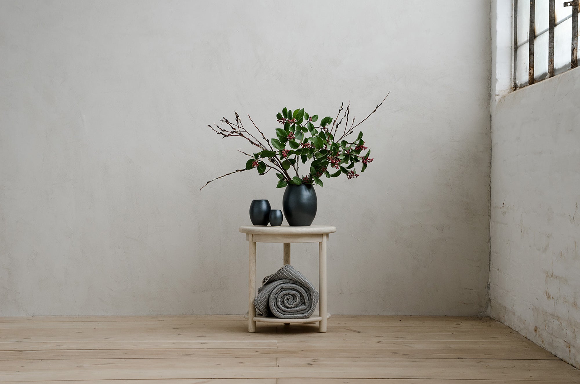 Scribe Side Table With Flowers on Top and a Blanket in the Base